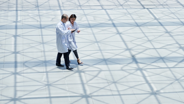 Two doctors discussing medical files in the foyer of a large commercial building
