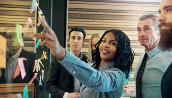 Co-workers discussing Post-It notes attached to a white board