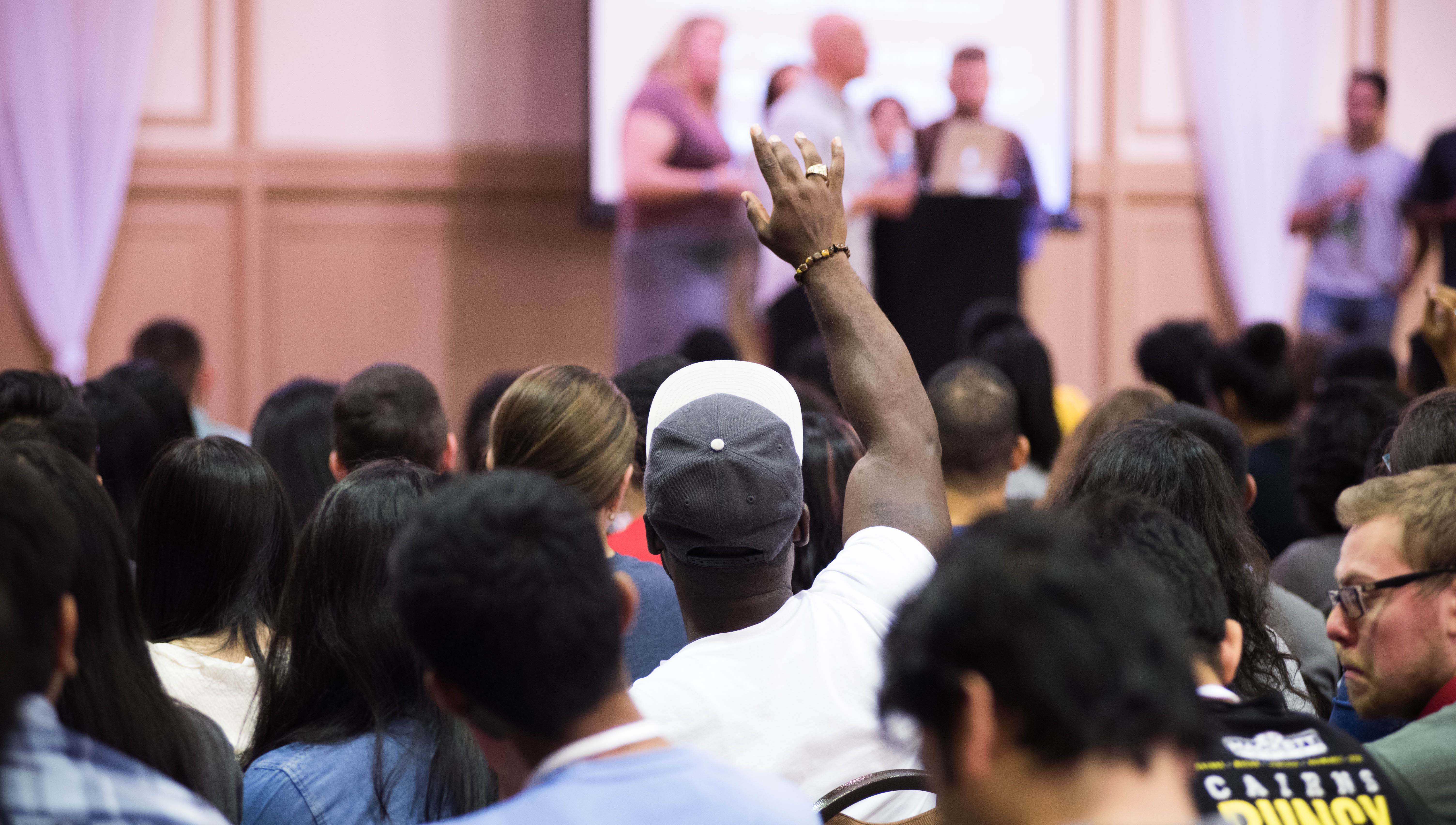 Student raising his hand in a  classroom setting.