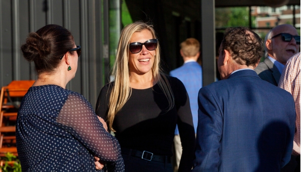 Smiling colleagues talk outdoors at a networking event.