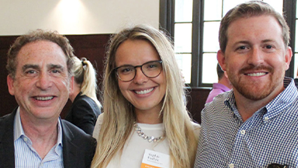 Associate Dean Andy Wasser and two individuals pose in a group photo in the Heinz College rotunda.