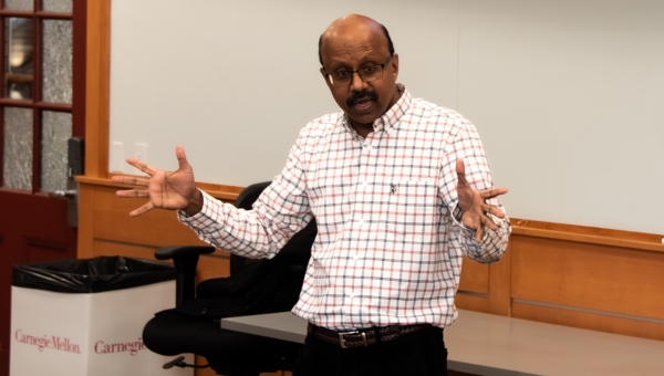 Professor Raja Sooriamurthi gesturing with his arms while giving a lecture.