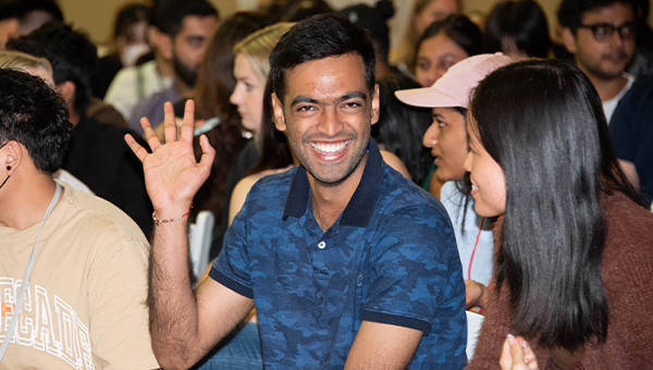 Student waving to camera at orientation event.