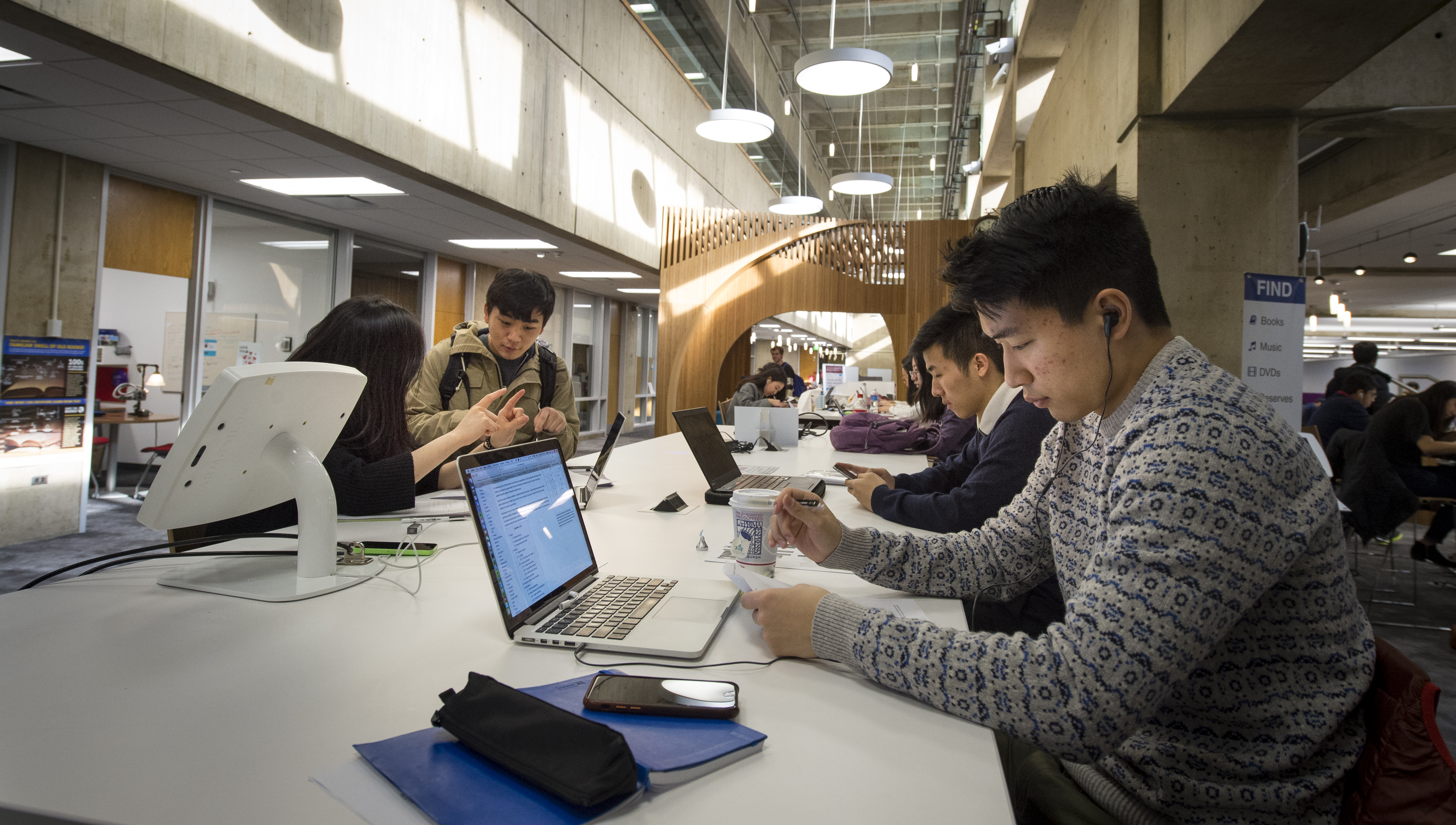 Student sitting at a library working on their laptop computers