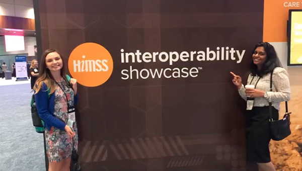 Students stand in front of a sign reading HIMSS Interoperability Showcase