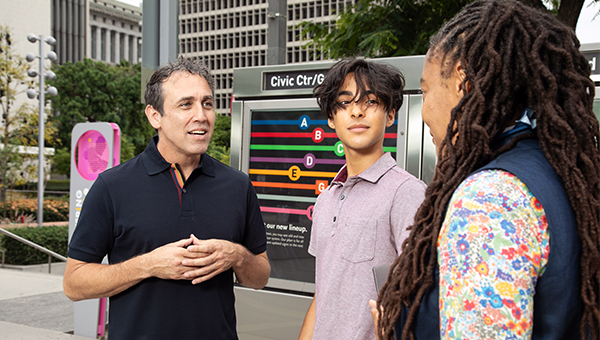 Samir Bitar chats with two people in front of a directional sign.