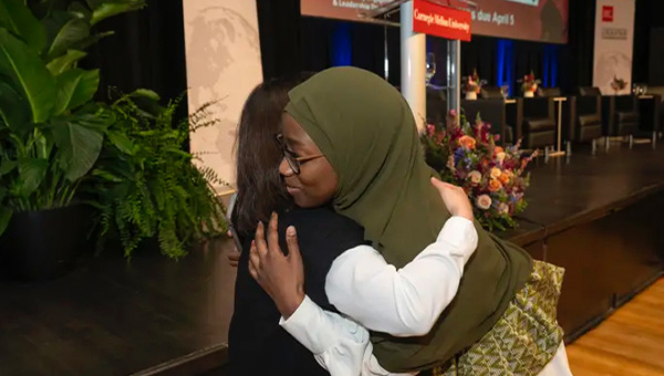 Anna Sene hugs an attendee at a peacebuilding event.