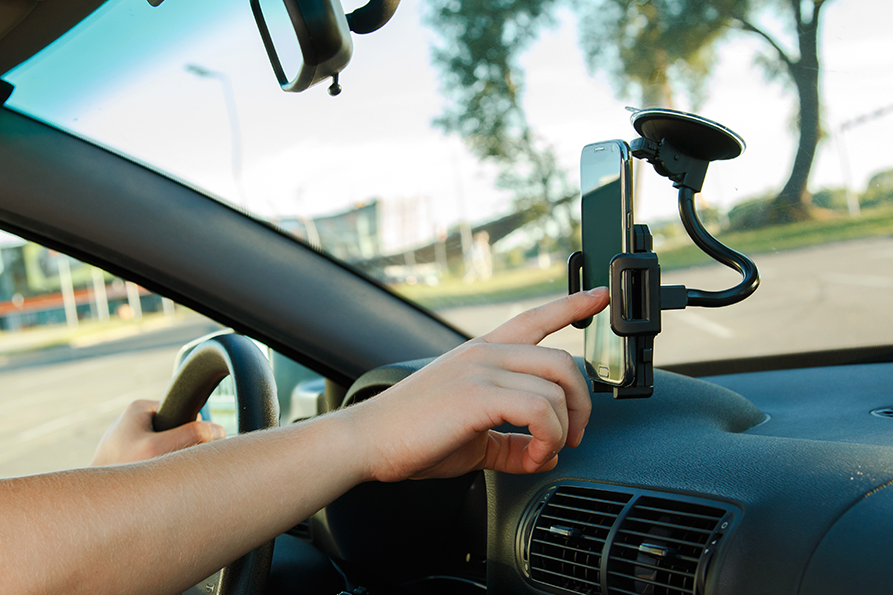 Person driving in a car and looking at navigation on their smart phone