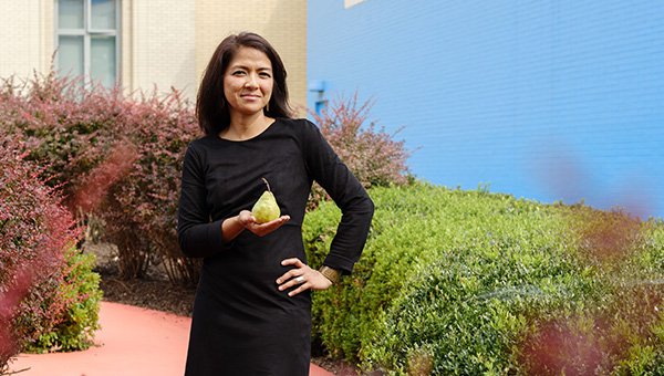 Leah Lizarondo posing with a pear on CMU's campus