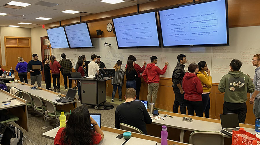 Students work at the front of the classroom in small groups.