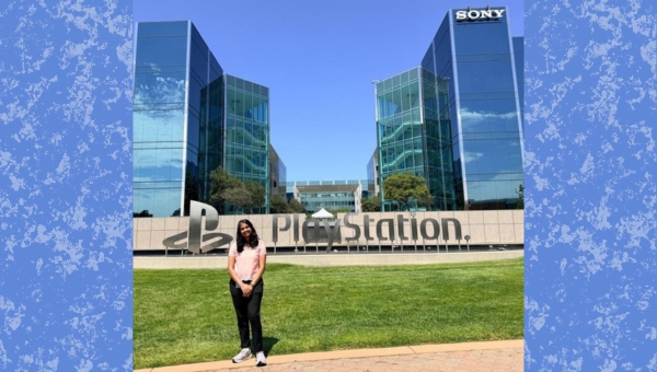 Dhiksha Rathis smiles in the foreground. In the background, the PlayStation and Sony signs are visible.