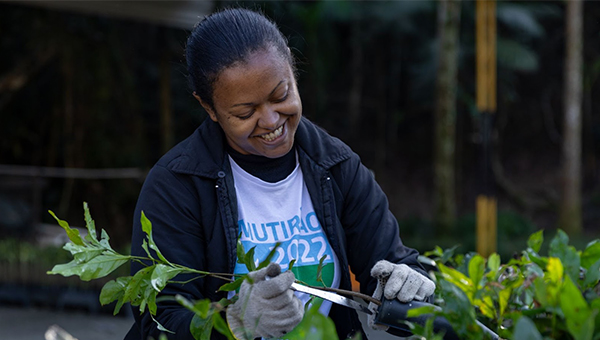 A woman smiles while planting a seedling.