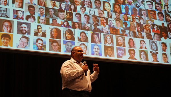 Professor Rayid Ghani speaking in front of a mosaic of faces