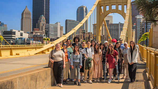 A group of MAM students stand on a yellow bridge in Pittsburgh.